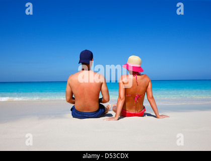 Junges Paar sitzt am tropischen Strand Stockfoto