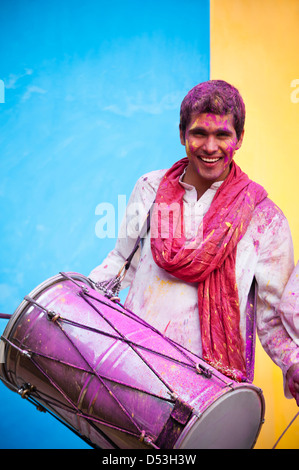 Lächelnder Mann feiern Holi mit spielen dhol Stockfoto