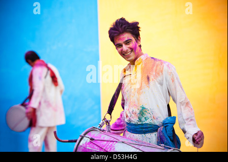 Lächelnder Mann feiern Holi mit spielen dhol Stockfoto