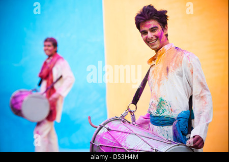 Lächelnder Mann feiern Holi mit spielen dhol Stockfoto