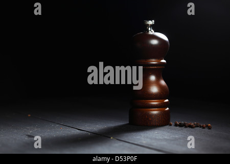 Aus Holz Pfeffermühle mit Pfefferkörnern auf schwarzen Tisch Stockfoto