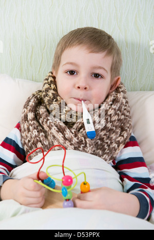 Kranken kleinen Jungen im Bett liegend mit Thermometer im Mund Stockfoto