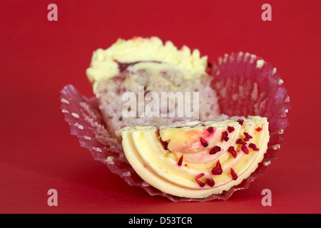 Tesco Finest leidenschaftliche Himbeer Cupcake halbieren auf rotem Hintergrund isoliert Stockfoto