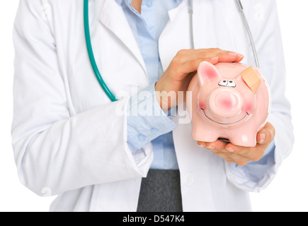 Closeup auf Arzt Frau mit Sparschwein mit Patch am Ohr Stockfoto