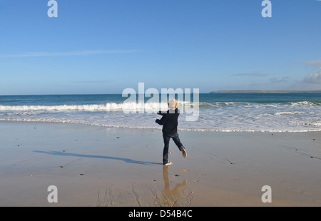 Junger Mann wirft Steinen ins Meer in St. Ives, Cornwall Stockfoto