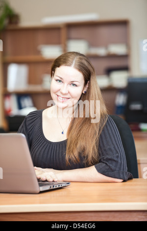 Glücklich lächelnde Frau eine Brünette mit Laptop im Büro Stockfoto