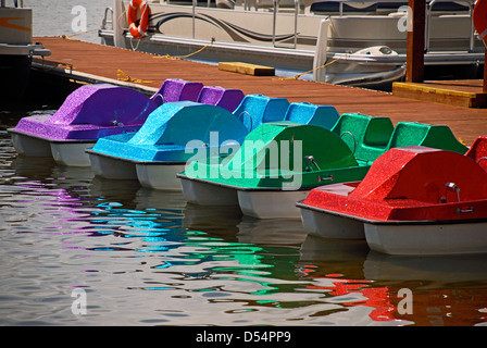 Vier bunte Tretboote erwarten Kunden eine kleine Anlegestelle am Ufer eines Sees in Colorado. Stockfoto