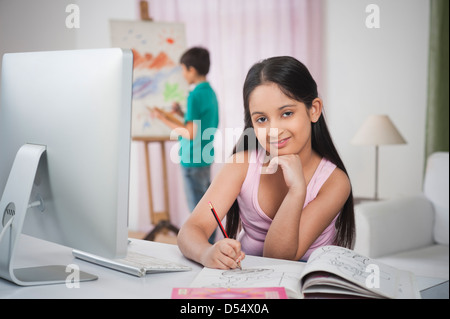 Mädchen an einen Schreibtisch mit ihrem Bruder auf Künstler-Leinwand Malerei studieren Stockfoto