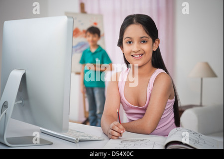 Mädchen an einen Schreibtisch mit ihrem Bruder auf Künstler-Leinwand Malerei studieren Stockfoto