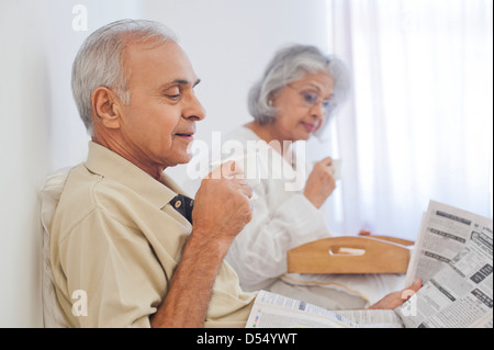 Älteres Paar, Tasse Tee mit Zeitunglesen auf dem Bett Stockfoto