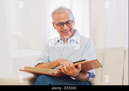 Ältere Menschen sitzen auf dem Sofa und beobachtete Fotoalbum Stockfoto