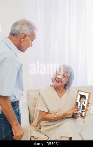 Älteres Paar beim Betrachten ihrer graduate Söhne Foto lächelnd Stockfoto