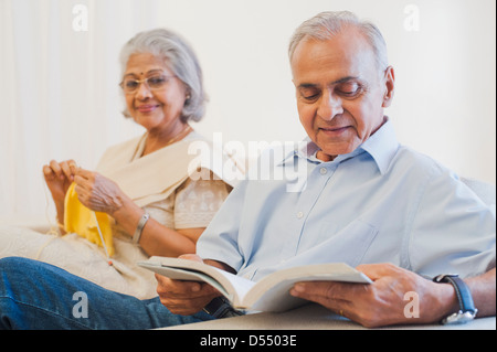 Ältere Mann ein Buch mit seiner Frau zu Hause stricken Stockfoto