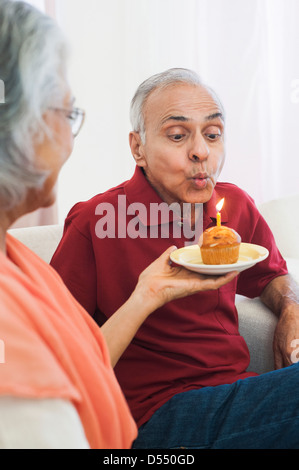 Ausblasen der Kerzen auf einen Cupcake während seinem Geburtstag Mann Stockfoto