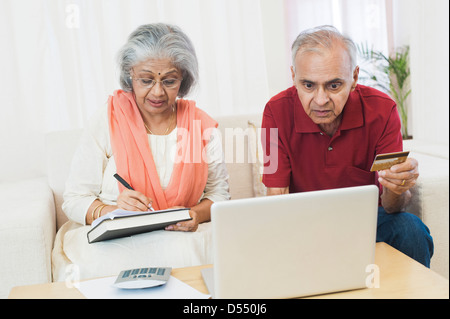 Älteres Paar, die Prüfung der Rechnungen auf einem laptop Stockfoto