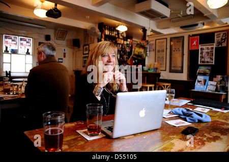 Frau bei der Arbeit auf einem Apple Macbook Pro Laptop-Computer in einer Kneipe Stockfoto