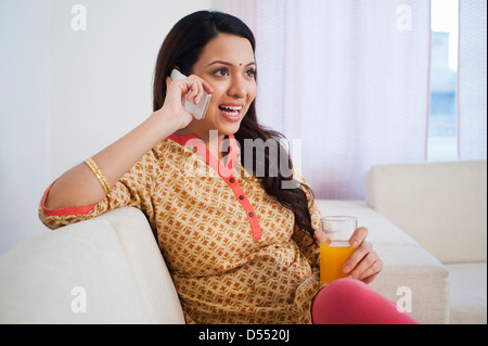 Glückliche Frau hält ein Glas Orangensaft und telefonieren mit einem Handy Stockfoto