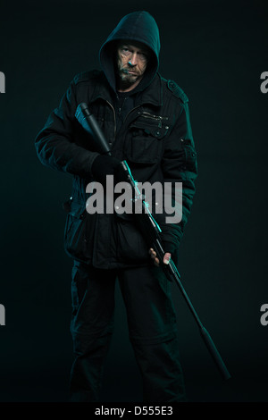 Sniper mit Bart in schwarz Holding Waffe. Studio gedreht. Stockfoto