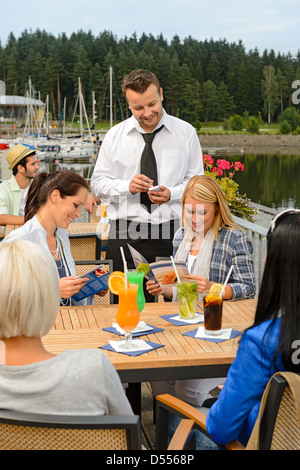 Kellner die Bestellungen an Bürgersteig Bar von jungen Frauen Stockfoto