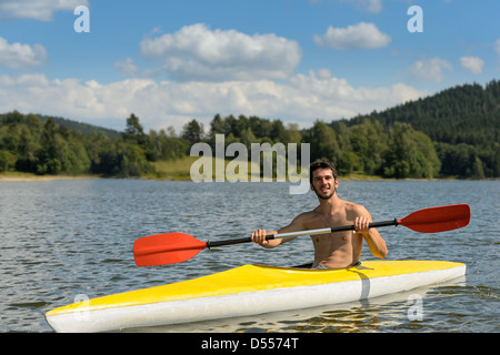 Junge Sportler Kajak an sonnigen Tag auf See Stockfoto