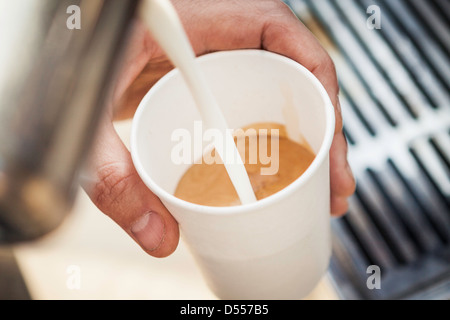 Nahaufnahme von Milch Eingießen in die Kaffeetasse Stockfoto