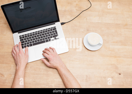 Mans Hände, Laptop und Kaffeetasse Stockfoto