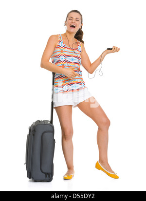 Lächelnde junge Touristen Frau mit Laufradtasche Musik hören und tanzen Stockfoto