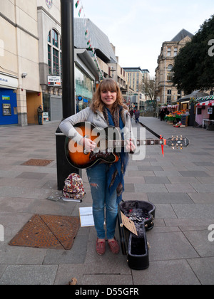 Junge attraktive weibliche Buskerin Sophie spielt ihre Gitarre auf einem Cardiff City Centre Street Wales Großbritannien Großbritannien KATHY DEWITT Stockfoto