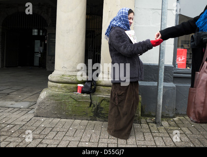 Eine junge Frau, die das Magazin Big Issue an einen verkauft Kunde zahlt Geldmünzen auf der Straße in Crickhowell Wales UK KATHY DEWITT Stockfoto