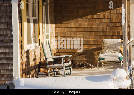 Schaukelstuhl und Schnee auf der Veranda des vakanten Hütte im Winter. Stockfoto