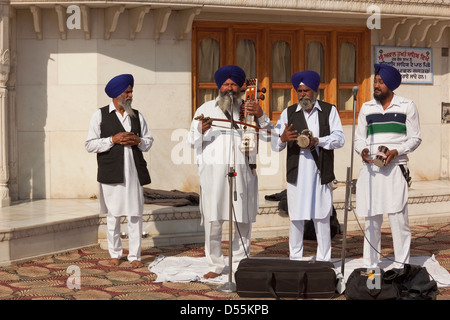 Vier männliche Musiker und Geschichtenerzähler mit traditionellen Punjabi Instrumenten auf den goldenen Tempel, Amritsar, Punjab, Indien Stockfoto