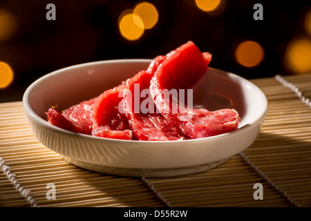 In Scheiben geschnitten, rote, rohe Fleisch in einer weißen Schale auf einer Bambusmatte Stockfoto