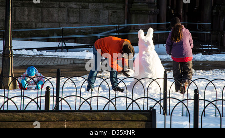 Eine Familie baut ein Osterhase aus Schnee im Copley Square Park. Boston, MA Stockfoto