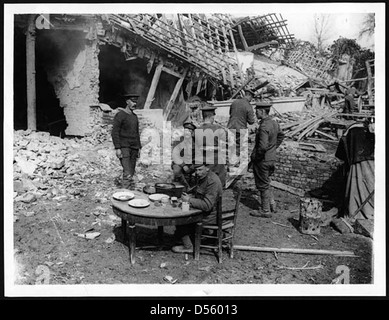 Britische Soldaten („Tommies“), die während des Ersten Weltkriegs in einem eroberten Dorf zu Abend essen. Dieser Moment veranschaulicht das tägliche Leben der Soldaten in besetzten Gebieten und die vorübergehende militärische Besatzung. Stockfoto
