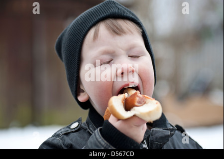 Kleiner Junge einen Hotdog mit Ketchup im Freien zu essen Stockfoto