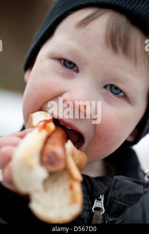 Kleiner Junge einen Hotdog mit Ketchup im Freien zu essen Stockfoto