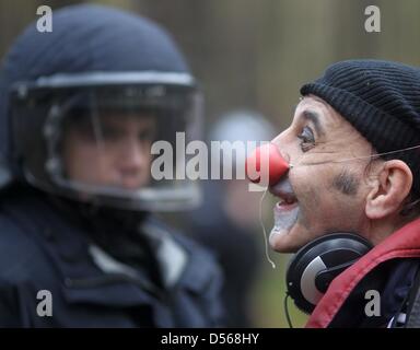 Ein Anti-Atom-Aktivist gekleidet wie ein Clown (R) steht ein Polizist gekleidet in Kampfmontur während einer Protestkundgebung gegen den Castor Nukleartransporten in entlang der Wailway in der Nähe von Leistade, zwischen Lüneburg und Dannenberg, Deutschland, 7. November 2010 verfolgt. 12. Lieferung von Atommüll aus der französischen Wiederaufbereitungsanlage in La Hague soll bei der Zwischenlagerung Facil ankommen Stockfoto