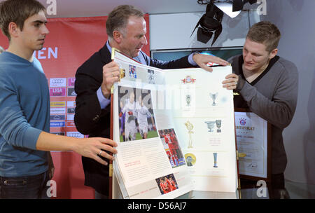 Bayern Spieler Philipp Lahm (L) und Bastian Schweinsteiger (R) und Vorsitzender des FC Bayern München Karl-Heinz Rummenigge die größte Bayern München-Chronik je gemacht während einer Pressekonferenz in München, Deutschland, 10. November 2010 präsentieren. Nach FC Bayern München das Buch mit dem Titel 4 Sterne - 111 Jahre 70x50cm groß und wiegt ca. 30 kg - so dass es die größte so Stockfoto