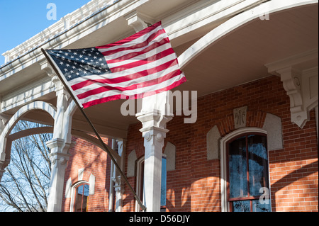 Amerikanische Flagge winken von der Veranda Beiträge von den historischen Walton County Courthouse auf dem Platz in der Innenstadt von Monroe, Georgia. Stockfoto