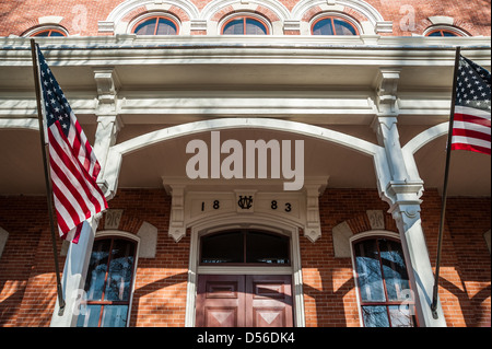 Amerikanische Flaggen wehten von der Veranda-Beiträge von der historischen Walton County Courthouse auf dem Platz in der Innenstadt von Monroe, Georgia. Stockfoto