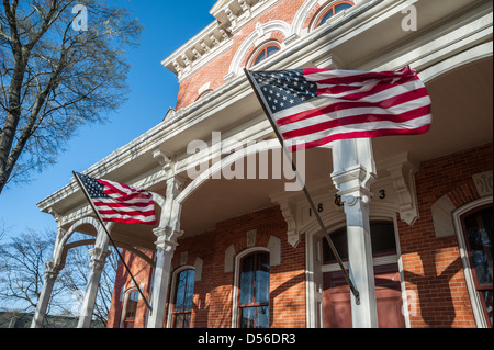 Amerikanische Flaggen wehten von der Veranda-Beiträge von der historischen Walton County Courthouse auf dem Platz in der Innenstadt von Monroe, Georgia. Stockfoto