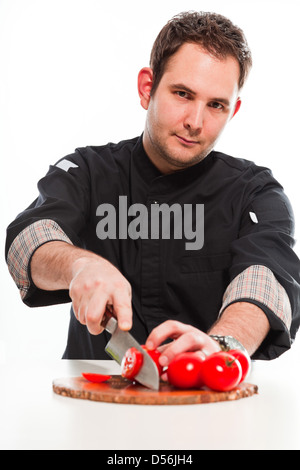 Junge männliche Koch mit schwarzen Jacke, die rohen Zutaten isoliert auf weiss. Stockfoto