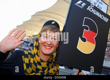 Eines der GulfAir Stewardessen als Grid Girl hält das Schild für deutsche Michael Schumacher Mercedes Grand Prix in der Formel ein Grand Prix von Bahrain in Sakhir Rennen in Bahrain, 14. März 2010 zu verfolgen. Schumacher wurde Sechster im ersten Rennen nach seiner dreijährigen Pause. Der Grand Prix von Bahrain startete die Formel1 Saison 2010. Foto: JENS Büttner Stockfoto