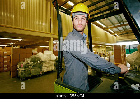 Kaukasische Arbeiter fahren Maschinen im Lager Stockfoto