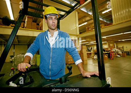 Kaukasische Arbeiter fahren Maschinen im Lager Stockfoto