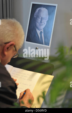 Ein Mann unterschreibt ein Kondolenzbuch neben einem Porträt des verstorbenen Wolfgang Wagner in Bayreuth, Deutschland, 24. März 2010. Ehemalige deutsche Leiter der Bayreuther Festspiele, Wolfgang Wagner, starb im Alter von 90 am 21. März 2010. Die Bayreuther Festspiele plant eine offizielle Gedenkveranstaltung für 11. April 2010. Foto: DAVID EBENER Stockfoto