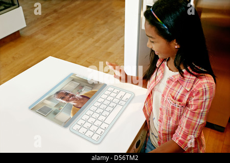 Mädchen, die Mutter in Computer in Tabelle winken Stockfoto