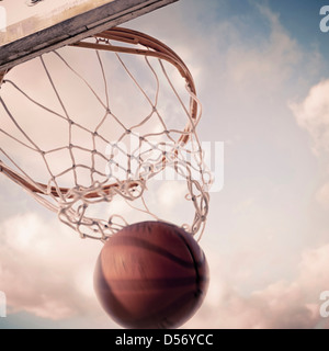 Basketball fallen durch Reifen auf Platz Stockfoto