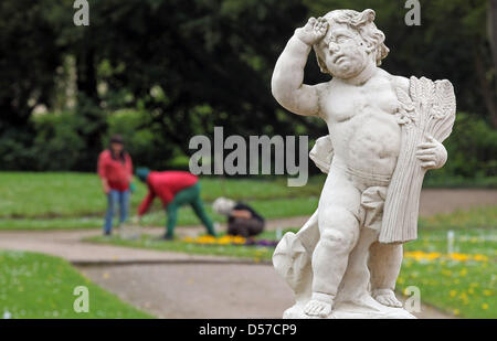 Hinter einer Engelsstatue arbeiten drei Gärtner in der barocken Garten von Schloss Lichtenwalde in Niederwiesa, Deutschland, 6. Mai 2010. Die im 18. Jahrhundert Barock Schloss zählt zu den schönsten Gärten Deutschlands. Foto: Jan Woitas Stockfoto