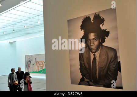 Besucher von der Presse-Preview der Ausstellung '' Basquiat'' vor einem Foto des Künstlers Jean-Michel Basquiaz am Museum der Fondation Beyeler in Riehen bei Basel, Schweiz, 7. Mai 2010 stehen. Auf der Occaision des 50. Geburtstages des 1988 verstorbenen Künstlers Jean-Michel Basquiet widmet die Fondation Beyeler eine große Retrospektive mit über 100 Gemälde, Papierarbeiten und ob Stockfoto